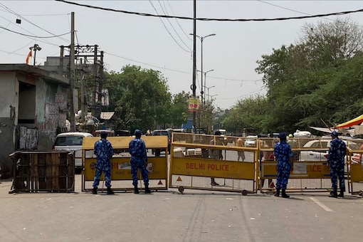 Riot policemen stand guard next to a barricade set up near a mosque and a temple a day after communal clashes in Jahangirpuri, a neighborhood in northwest Delhi, on April 17, 2022. (AP Photo/Rishi Lekhi)