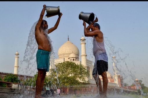 Locals cool themselves with water on a hot summer day at the Dussehra Ghat behind the Taj Mahal in Agra on April 25, 2022. (PTI Photo)