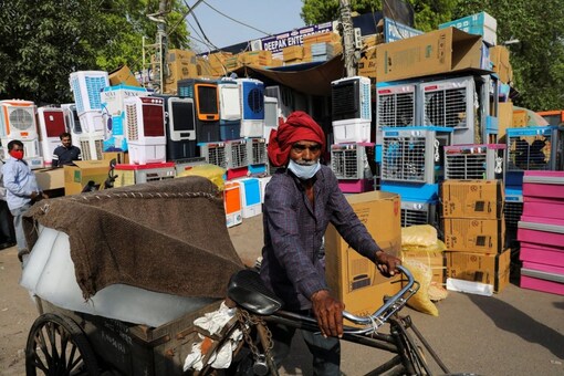 A man transports slabs of ice near an air cooler market on a hot summer day, in New Delhi, India, April 11, 2022. REUTERS/Anushree Fadnavis