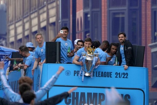 Manchester City's players pass by on an open top bus as soccer fans watch the winners parade as the team celebrates winning the English Premier League title in Manchester, England, Monday, May 23, 2022. (AP Photo/Jon Super)