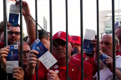 Liverpool fans show tickets and wait in front of the Stade de France ahead of the UEFA Champions League final (AP)