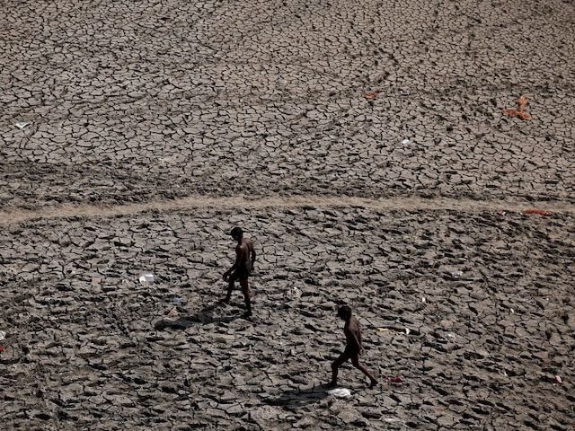 Men walk through an almost dry river bed. (Image: REUTERS/Adnan Abidi)