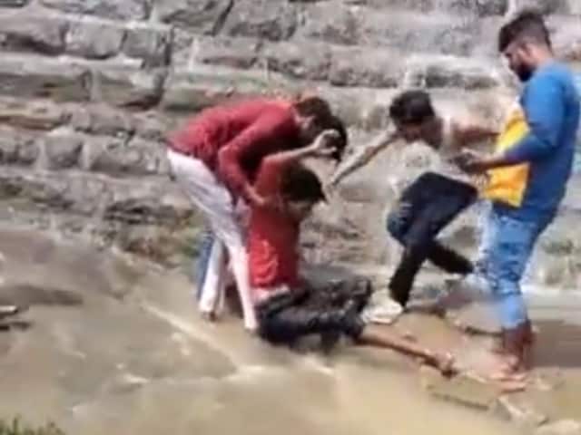 Some onlookers grabbed a youth after he fell from a height of 30 feet while scaling the wall of a dam in Karnataka. (Image: Twitter/video grab)
