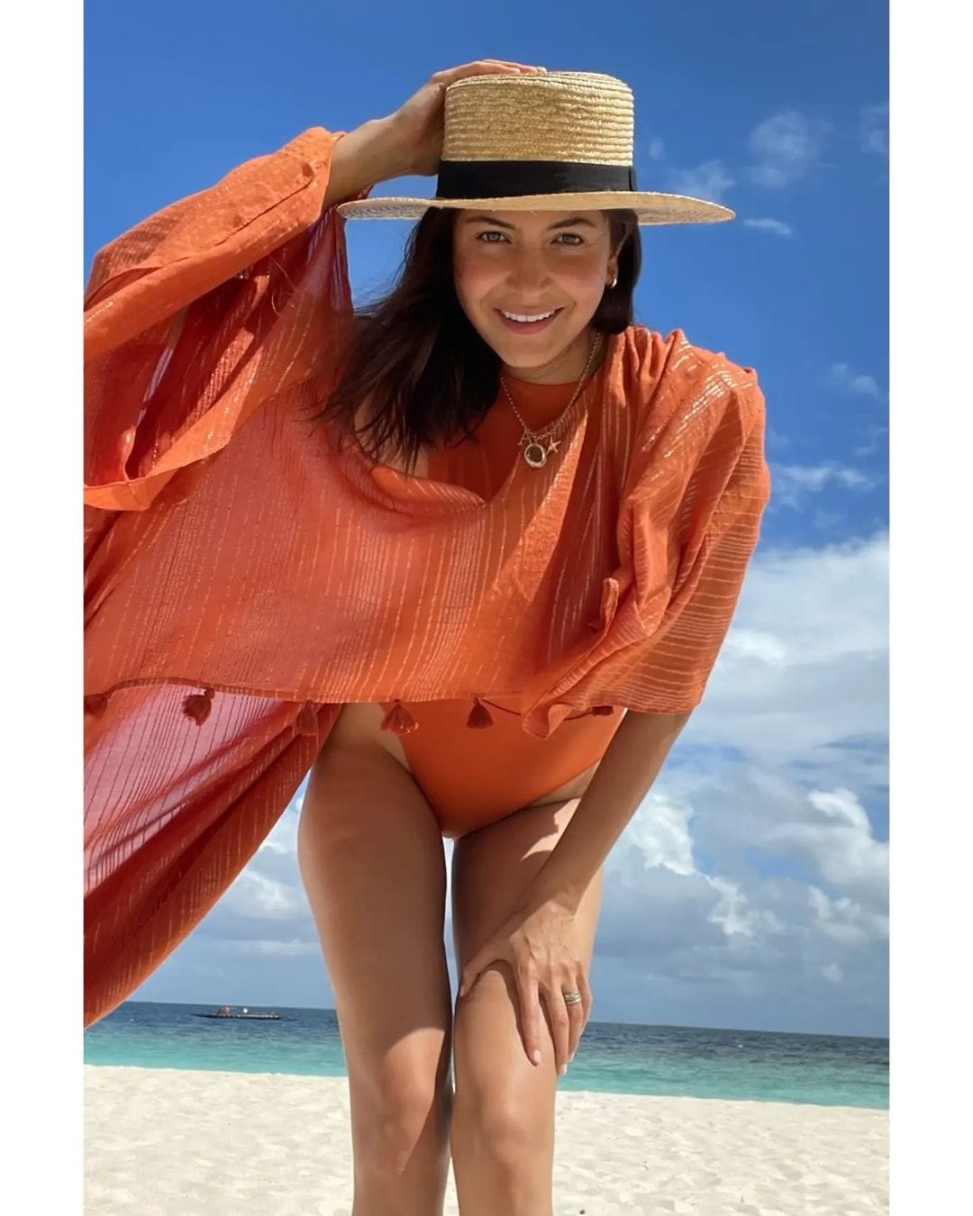Anushka Sharma at the beach in an orange swimsuit.