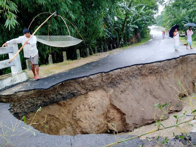 Locals inspect the flood-damaged Dhamdhama-Khatikuchi connecting road following heavy rains, in Baksa district. (PTI)