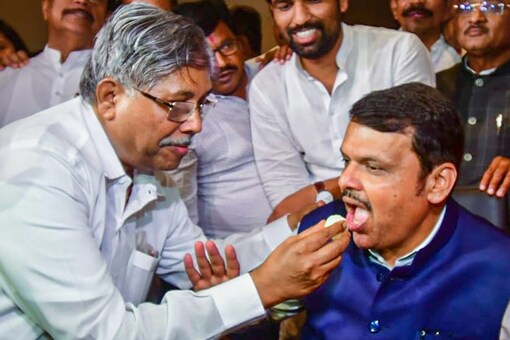 Former Maharashtra CM and BJP leader Devendra Fadnavis being fed sweets by state BJP president Chandrakant Patil during a party meeting, at Taj President Hotel in Mumbai on Wednesday. (Pic/PTI)