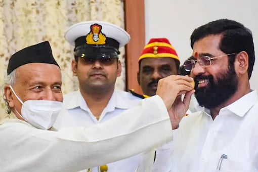 Maharashtra Governor Bhagat Singh Koshyari offers sweets to Eknath Shinde as he, along with BJP leaders and other supporting MLAs, stakes claim to form the government in the state. (Image: PTI File)