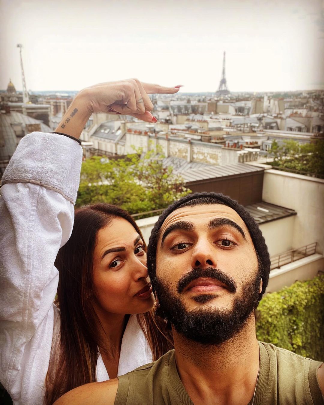 Malaika Arora points towards the Eiffel Tower as the couple pose for a selfie.