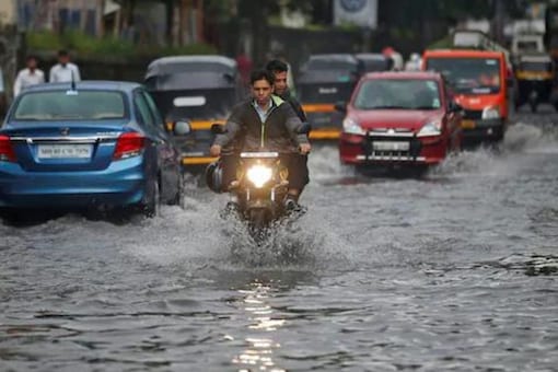 People commute through a water-logged road street after rains in Mumbai (Reuters)
