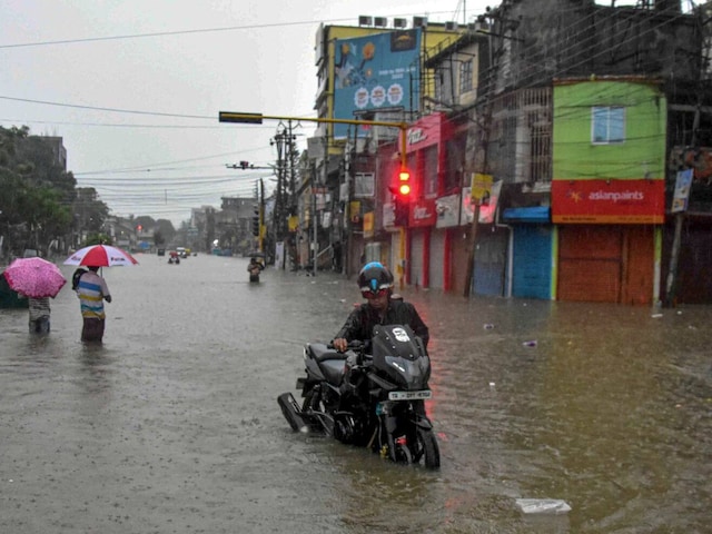 Commuters wade through a waterlogged street after heavy rains in Agartala. (PTI)