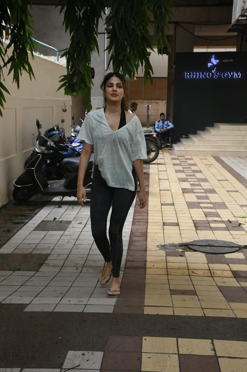 Rhea Chakraborty sported a white top with a black bralette and matching jeggings as she stepped out of her gym. (Image: Viral Bhayani)