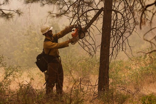 A U.S. Forest Service firefighter clears brush amid a fire. REUTERS