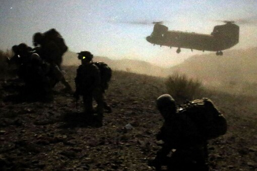 US and Afghan soldiers take a knee near a US Army Chinook during an operation near the town of Walli Was in Paktika province in November 2012. (Image:  REUTERS/Goran Tomasevic/File)