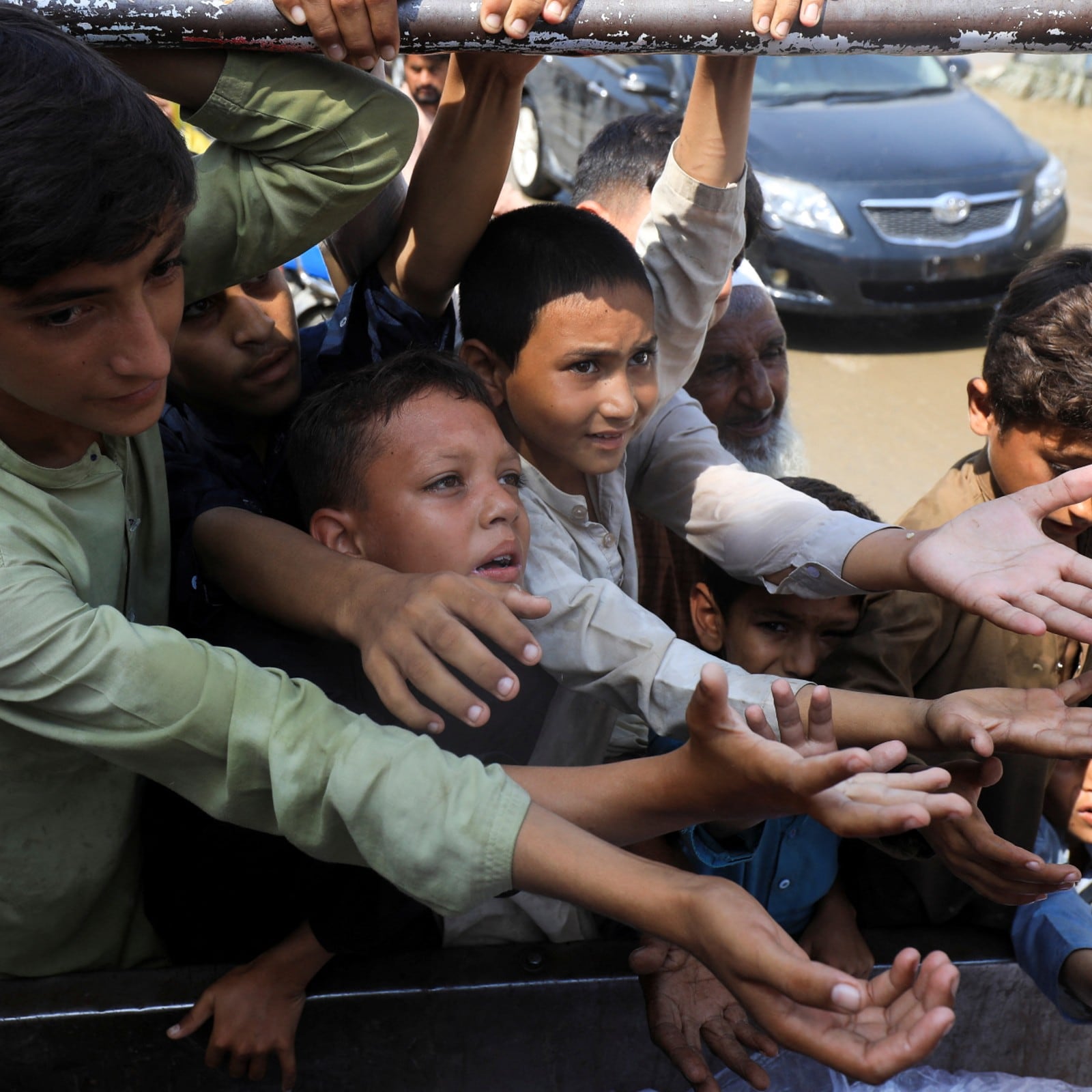 Boys, victims of the flood, reach out for food from a relief worker, following rains and floods during the monsoon season in Nowshera, Pakistan (Reuters Image)