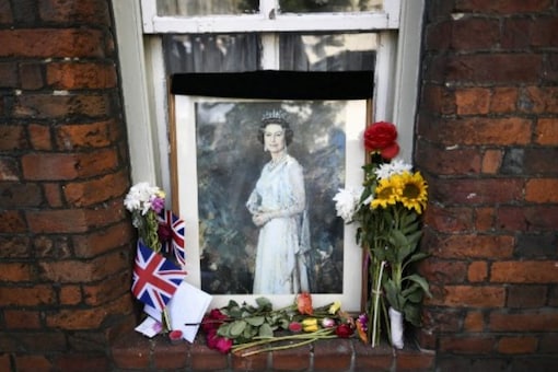 A picture of Britain's Queen Elizabeth II and floral tributes are displayed in a window in Windsor on September 18, 2022, following the death of Queen Elizabeth II on September 8. (AFP)