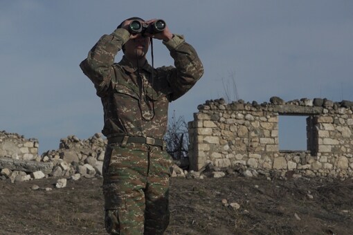 An ethnic Armenian soldier looks through binoculars as he stands at fighting positions near the village of Taghavard in the region of Nagorno-Karabakh (Image: Reuters)