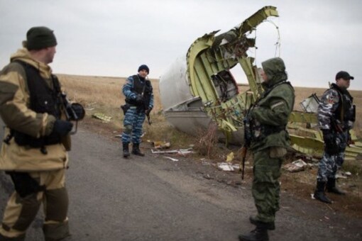 In this file photo taken on November 11, 2014, pro-Russian gunmen guard as Dutch investigators arrive near parts of the Malaysia Airlines Flight MH17 at the crash site in eastern Ukraine. (AFP)