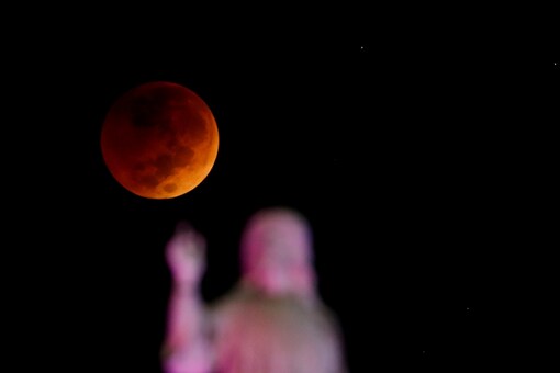 The moon and a statue are seen during a lunar eclipse in San Salvador, El Salvador, November 8, 2022. (REUTERS/Jose Cabezas)