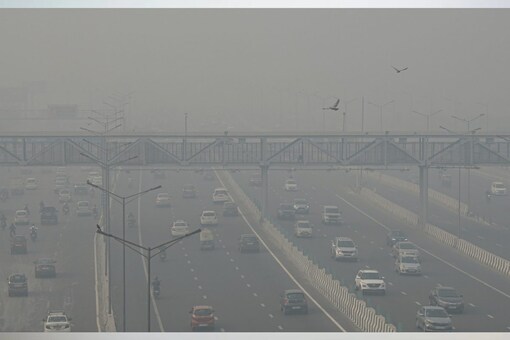 Vehicles ply on a road near Akshardham Temple amid low visibility due to a thick layer of smog, in New Delhi (PTI Photo)