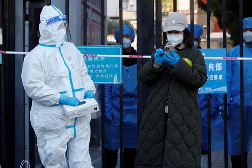 Security personnel in protective suits stand at the gate of a residential compound that is under lockdown in Beijing (Image: Reuters)