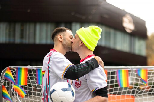 Protestors kiss while holding a football (AP)
