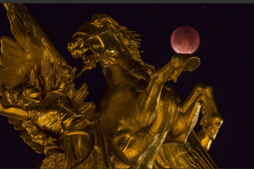 The Moon, appearing next to a statue on the Alexander III bridge, in a dim red colour, is covered by the Earth's shadow during a total lunar eclipse over Paris, France September 28, 2015.  (Image: Reuters/FILE)