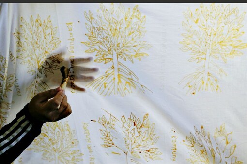 A mangrove batik worker draws a batik pattern on a white cotton cloth in Klaces village, Indonesia, November 4, 2021. REUTERS/Ajeng Dinar Ulfiana