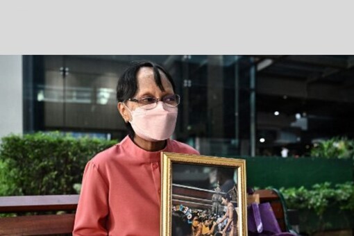 A well-wisher sits with a photo of Princess Bhajrakitiyabha Mahidol at Chulalongkorn Hospital in Bangkok on December 16, 2022. (AFP)