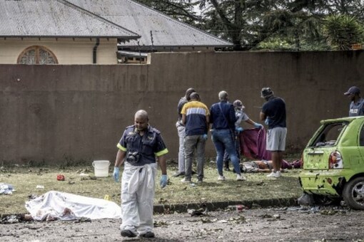 South African Police Service (SAPS) officers and forensic experts stand beside bodies in Boksburg, a city east of Johannesburg. (AFP)