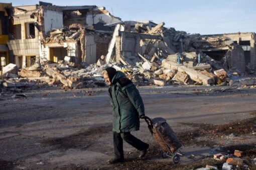 An elderly woman pulls a trolley bag past a destroyed building in Bakhmut, Donetsk region on December 4, 2022. (Image: AFP)