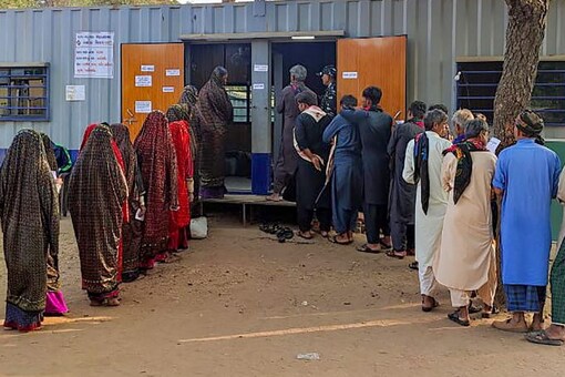 Bharuch: Voters wait in queues to cast their votes at a polling station made from shipping container during the first phase of Gujarat Assembly elections, at Aliabet, an isolated place in Bharuch district, Thursday. (PTI Photo)