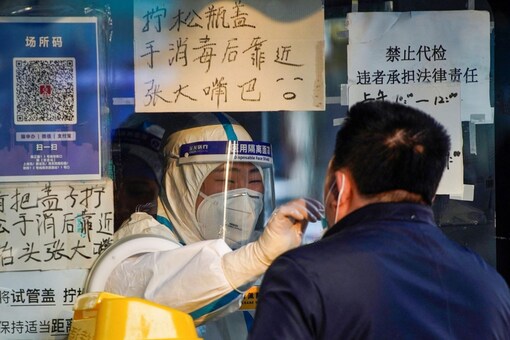 A medical worker in a protective suit collects a swab sample from a man at a nucleic acid testing site, as coronavirus disease outbreaks continue in Shanghai, China, December 12, 2022. REUTERS/Aly Song