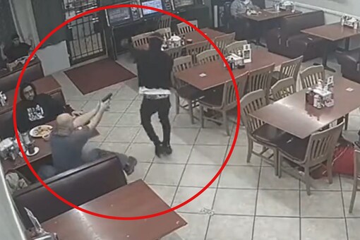 The unnamed armed customer (left) is seen shooting the robber (right) who is seen asking the patrons to give him their money and wallets (Image: Twitter/@rawsalerts)