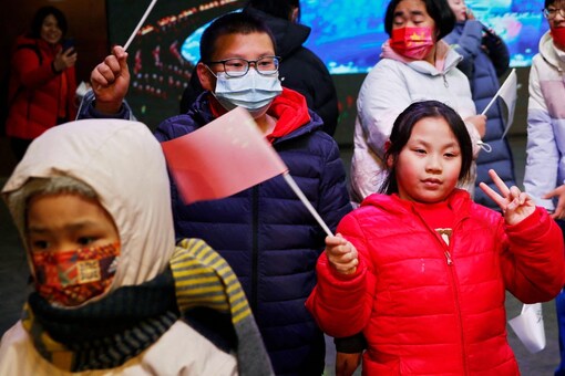 Children wave Chinese flags in front of a giant screen in Beijing, China (Image: Reuters)