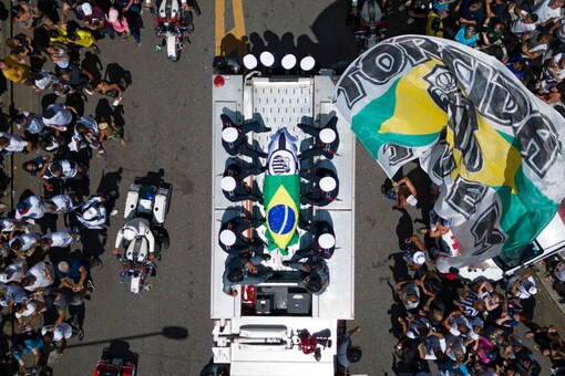 The casket of late Brazilian soccer great Pele is draped in the Brazilian and Santos FC soccer club flags as his remains are transported from Vila Belmiro stadium, where he laid in state, to the cemetery during his funeral procession in Santos (AP)