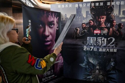 A young woman takes a picture of a poster before watching the movie Black Panther: Wakanda Forever at a cinema in Shanghai on February 6, 2023. (AFP)