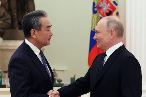 Russia's President Vladimir Putin shakes hands with China's Director of the Office of the Central Foreign Affairs Commission Wang Yi during a meeting in Moscow, Russia (Image: Reuters)