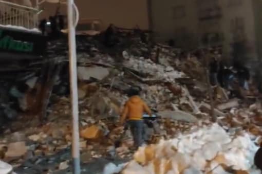 In this snapshot taken from an unverified video on Twitter, a man is seen walking amongst the rubble of a building which collapsed somewhere in south Turkey following a 7.9 magnitude earthquake (Image: Twitter)