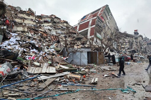 People stand in front of collapsed buildings following an earthquake in Kahramanmaras, Turkey on February 6, 2023. Ihlas News Agency (IHA) via REUTERS 