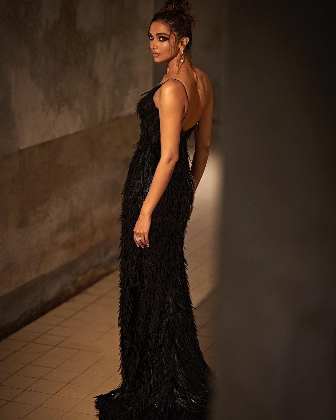 Deepika Padukone looks sexy in a figure-hugging black dress by Louis Vuitton.