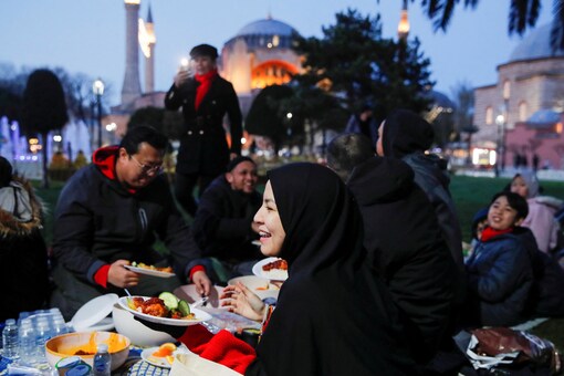 People, with the Ayasofya-i Kebir Camii or Hagia Sophia Grand Mosque in the background, have their iftar at Sultanahmet Square during first day of Ramadan in Istanbul. (Credits: Reuters)