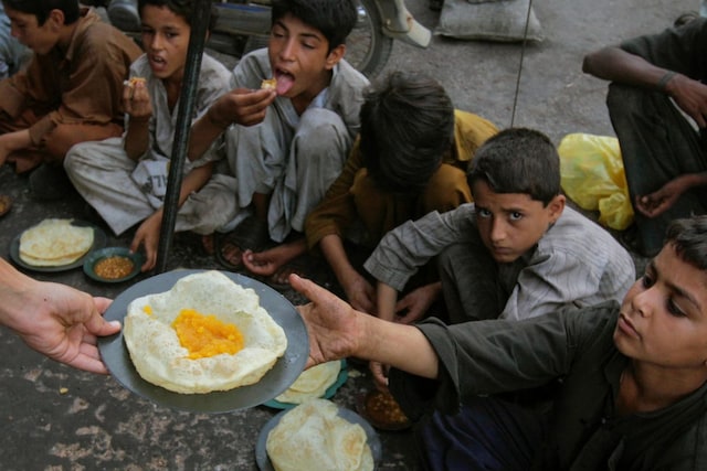 Children receive free food distributed outside a cafe, early morning in Karachi (Image: Reuters File)