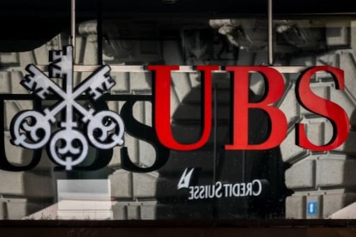 A photograph shows a logo of Swiss giant bank UBS in front of a logo of Credit Suisse bank in Zurich on March 19, 2023. (AFP)