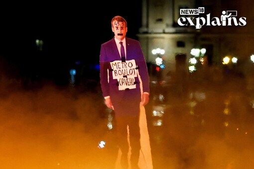 A protester holds a cut-out depicting French President Emmanuel Macron near fire during a demonstration on Place de la Concorde to protest the use by French government of the article 49.3. REUTERS/Gonzalo Fuentes 