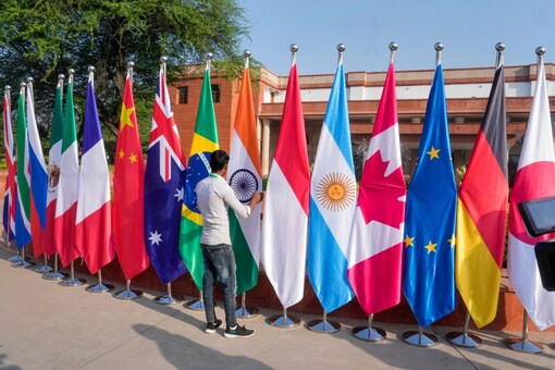 A worker arranges flags of participating countries, put up for the G20 Foreign Ministers' Meeting, at RBCC in New Delhi, Thursday, March 2, 2023. (PTI Photo/Manvender Vashist Lav)