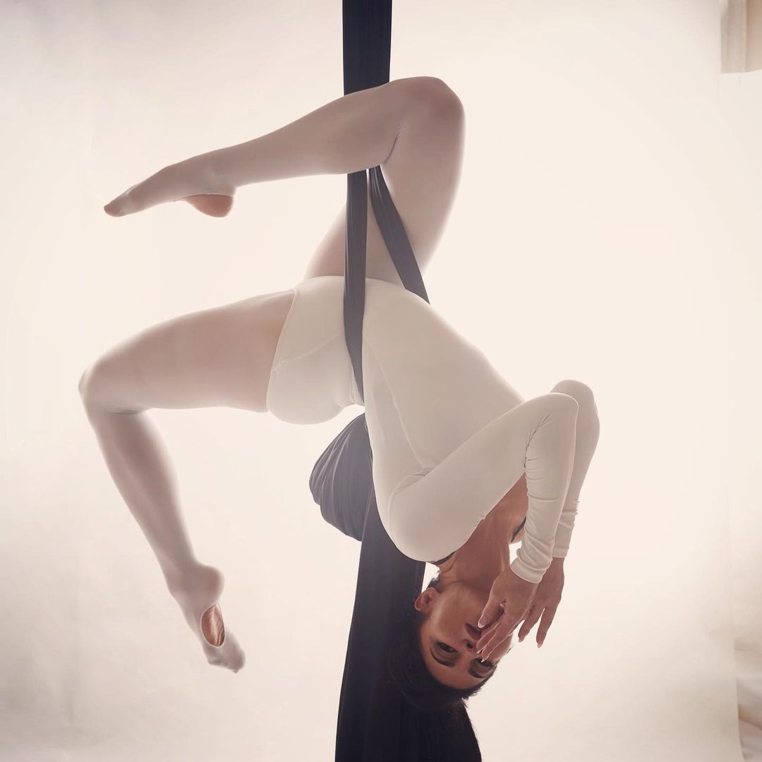 Jacqueline Fernandez holds a pose upside down while doing aerial yoga.