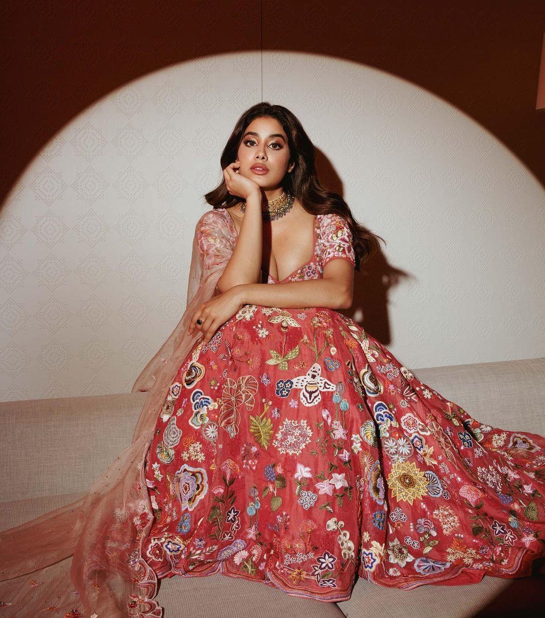 Janhvi Kapoor sits pretty in a floral-embroidered red lehenga.
