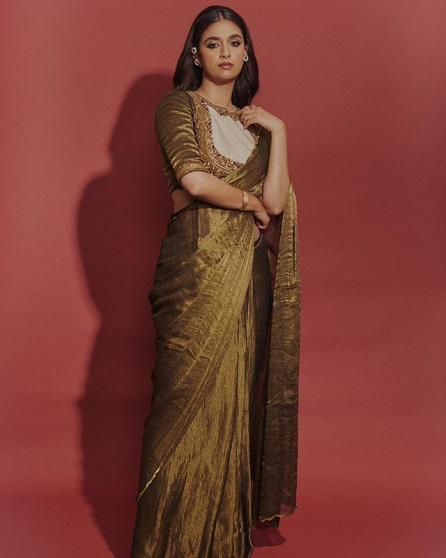Keerthy Suresh strikes a pose in a golden saree. The unusual blouse design makes it stand out. 
