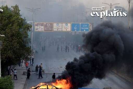 A car is seen burning along a road as Pakistan Tehreek-e-Insaf (PTI) party activists and supporters of former Pakistan's Prime Minister Imran block a road during a protest against the arrest of their leader in Karachi on May 9, 2023. AFP