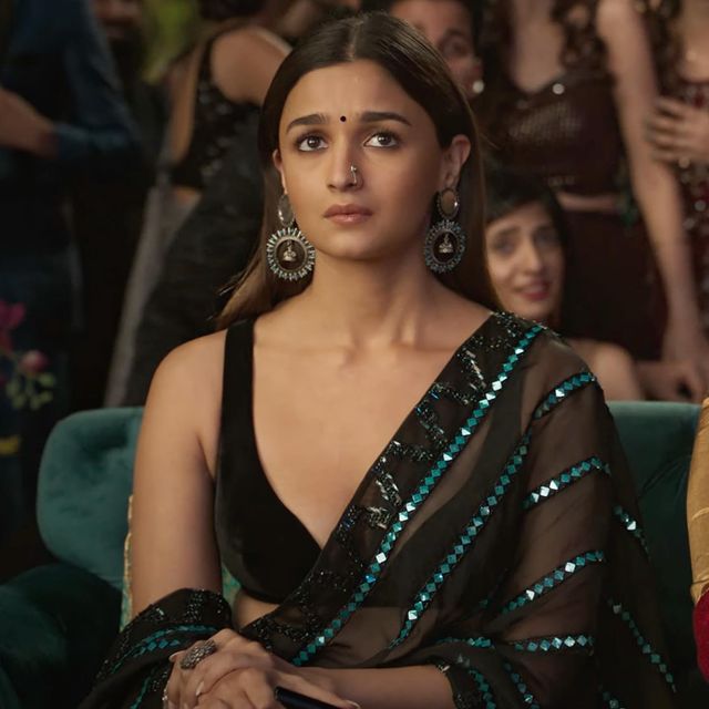 Alia Bhatt looks glamorous in the black see-through saree with blue embellishments. The huge earring and nose pin adds a nice touch to her saree look.